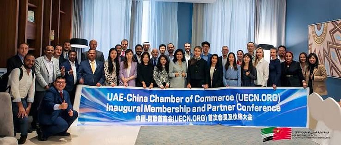 An Asian businessman and an Emirati professional shaking hands at a chamber of commerce networking event