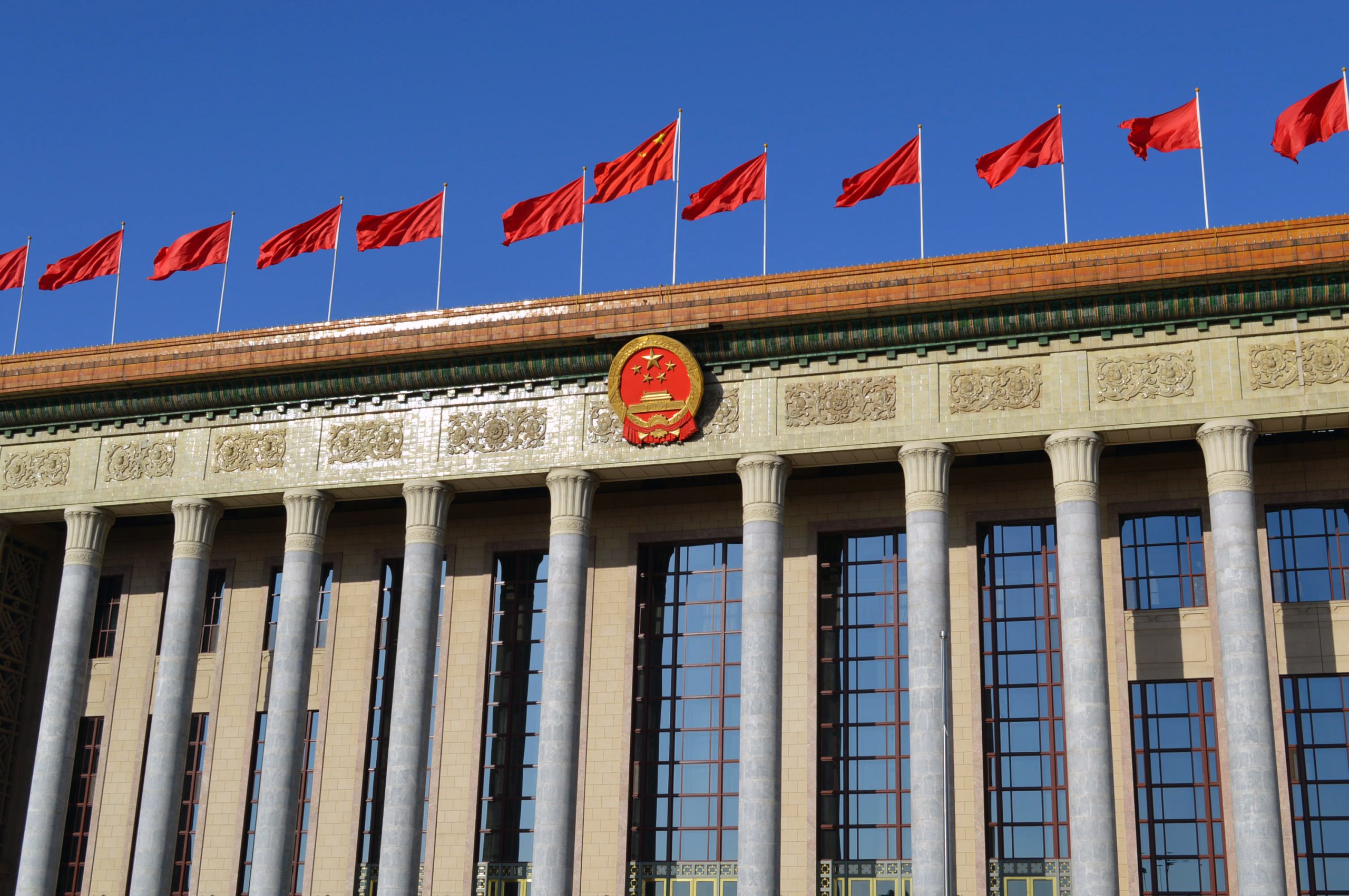 Great Hall of the People in Beijing decorated with Chinese national flags under a bright blue sky