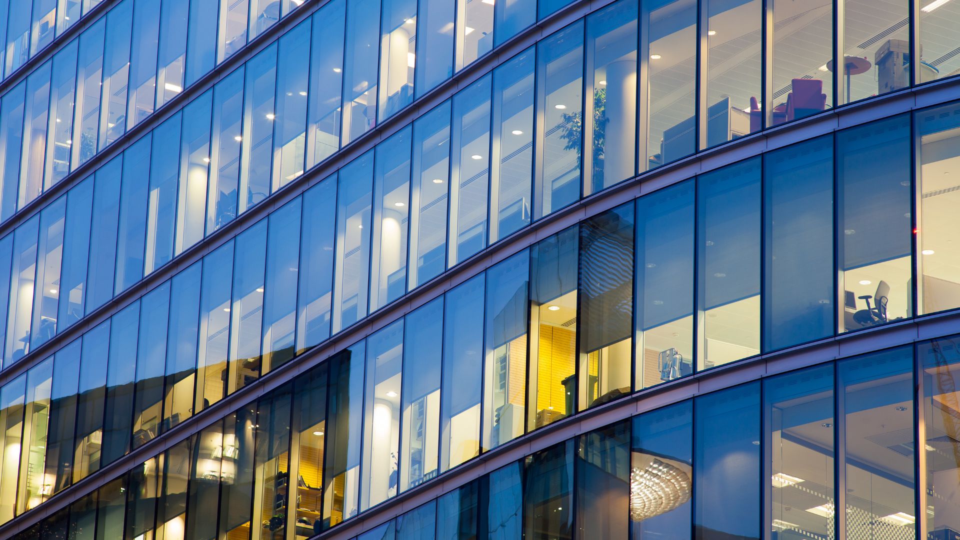 Modern illuminated glass facade of an office building at dusk