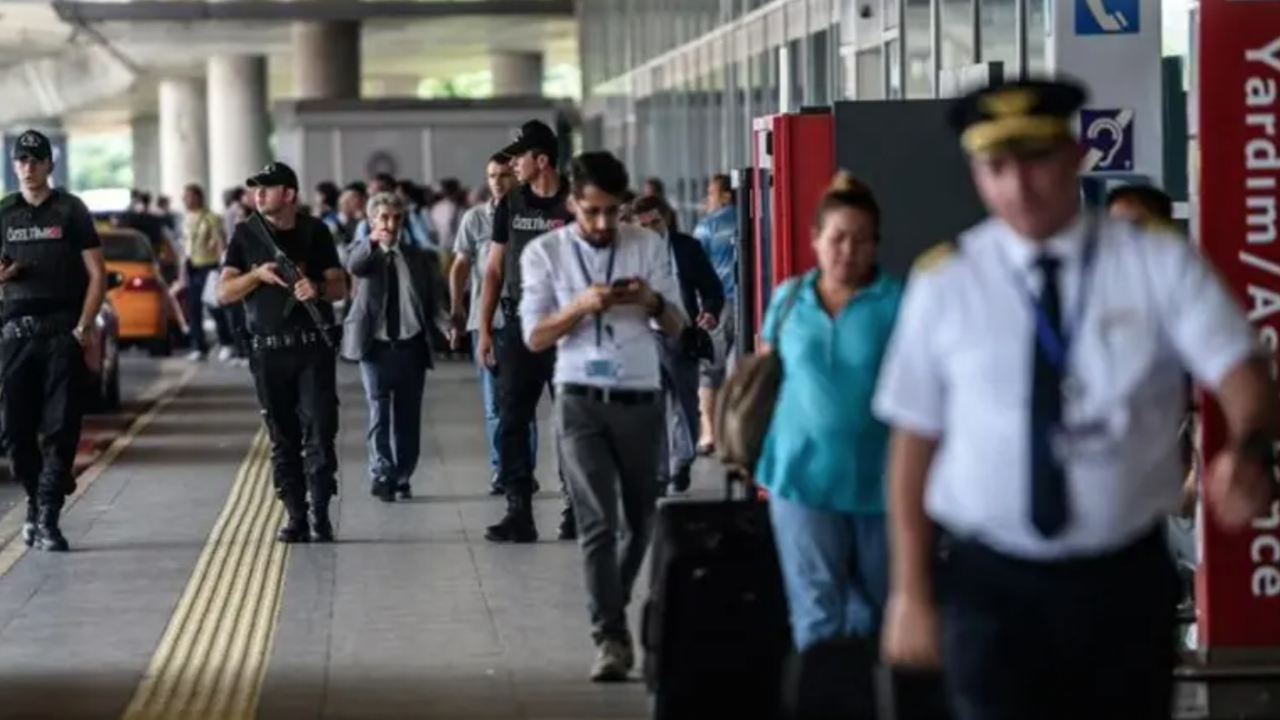 Armed security officers and travelers walking along an airport terminal sidewalk