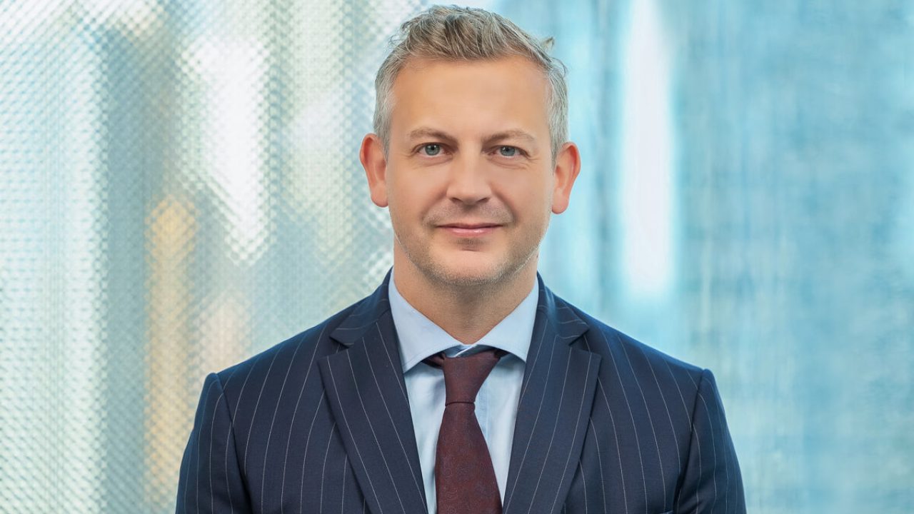 Portrait of a businessman in a pinstripe suit and tie against a blurred office window background