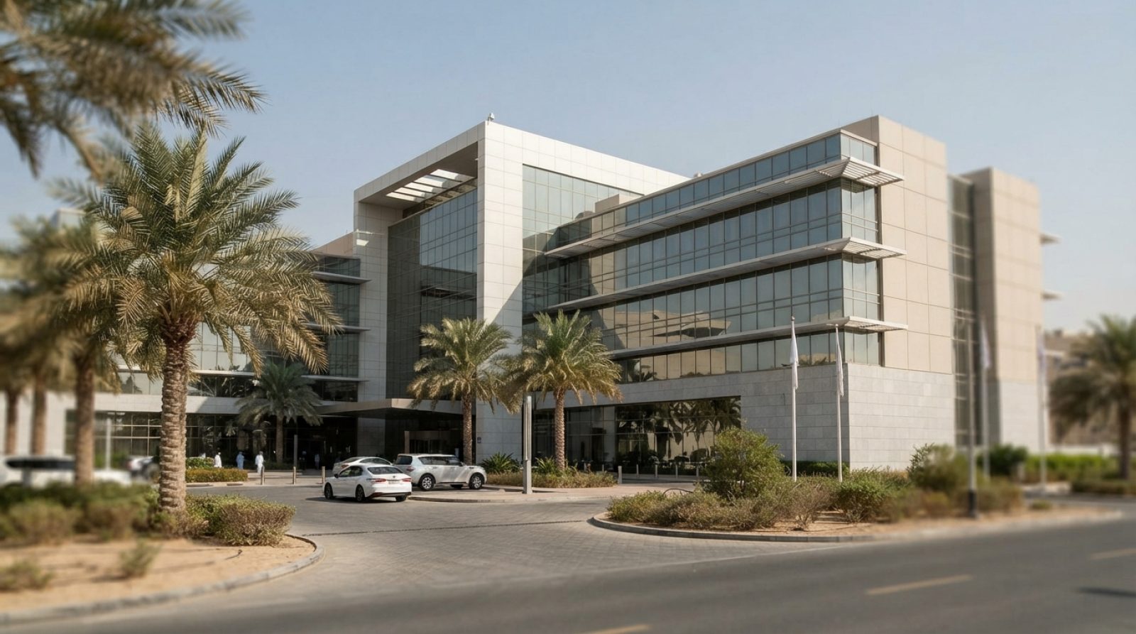 رسم توضيحي: واجهة زجاجية حديثة لمستشفى ومركز طبي في دولة الإمارات العربية المتحدة تحت ضوء النهار الصافي، مع أشجار نخيل صحراوية وممر سيارات معبد