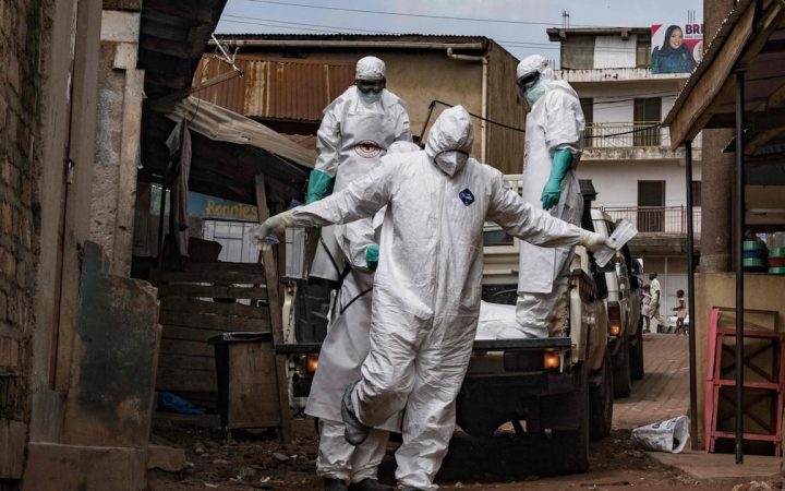 Health workers wearing full protective hazmat suits and masks stepping off a pickup truck in a street