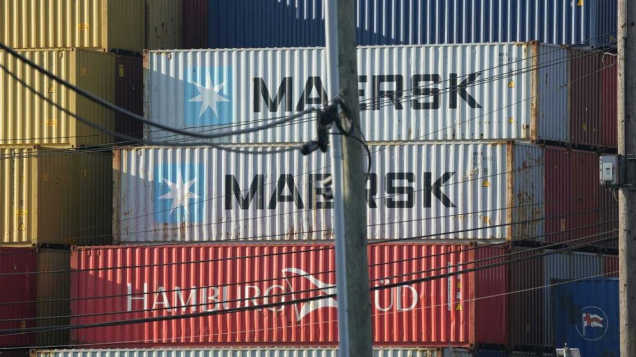 Stacked Maersk and Hamburg Sud shipping containers obstructed by a utility pole and overhead wires