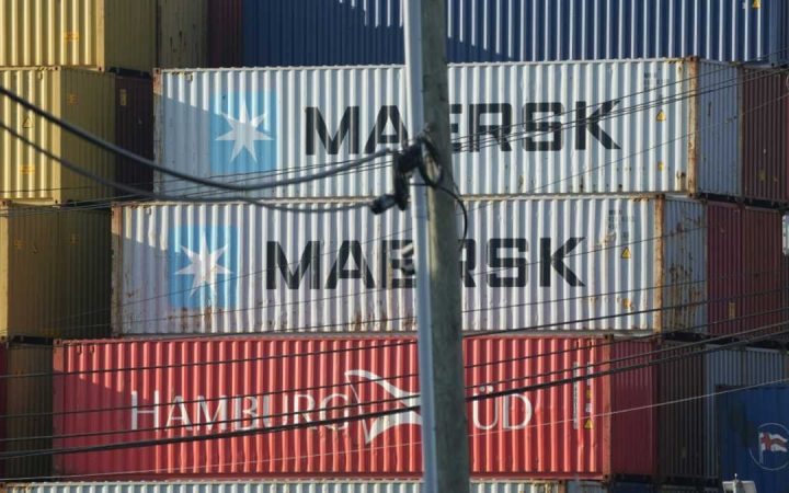 Stacked Maersk and Hamburg Sud shipping containers obstructed by a utility pole and overhead wires