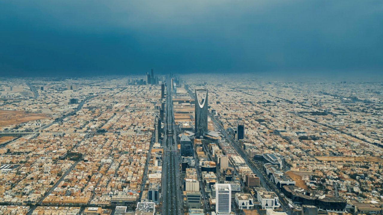 Aerial view of the Riyadh skyline featuring the Kingdom Centre under an overcast sky