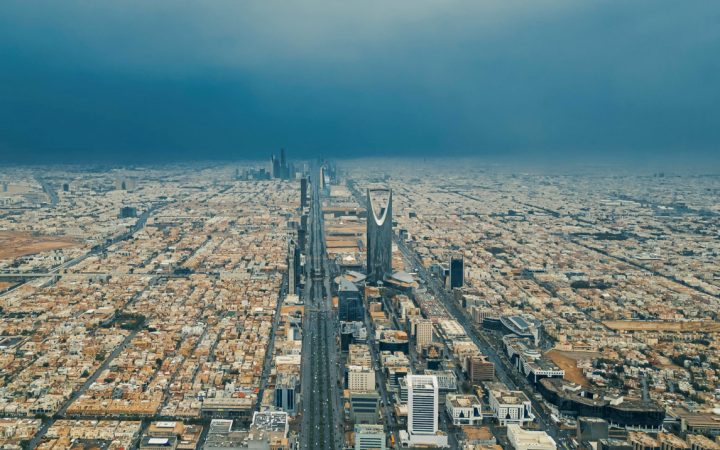 Aerial view of the Riyadh skyline featuring the Kingdom Centre under an overcast sky