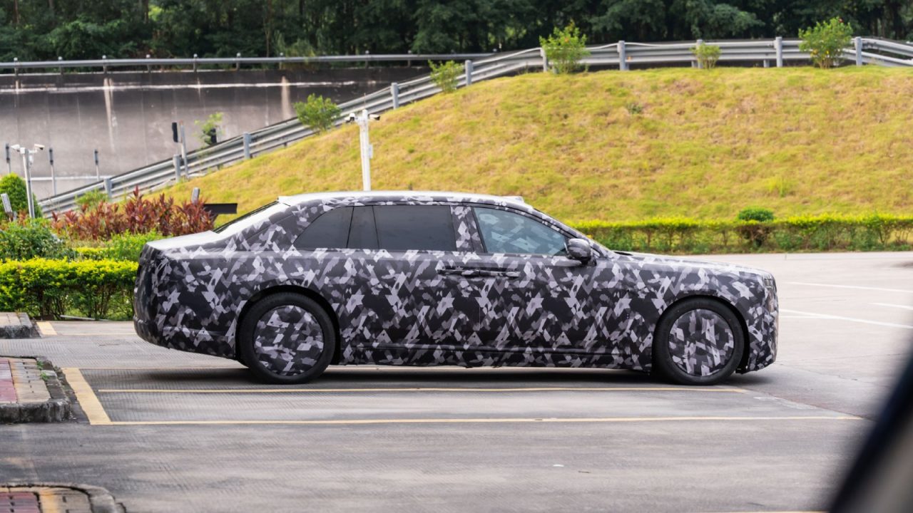 Side profile of a camouflaged luxury prototype car parked on asphalt