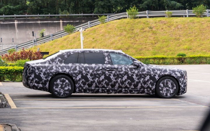Side profile of a camouflaged luxury prototype car parked on asphalt
