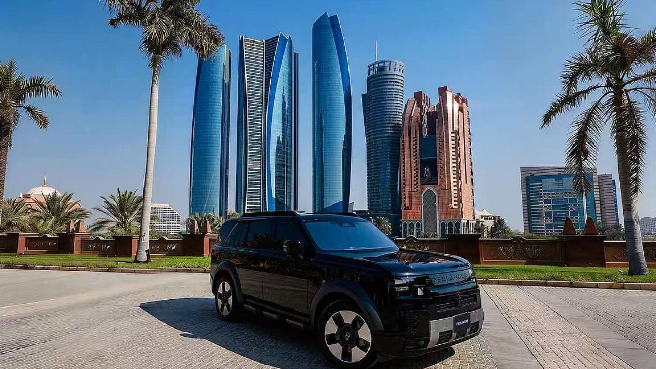 A black SUV parked in front of the modern Abu Dhabi skyline and palm trees under a blue sky