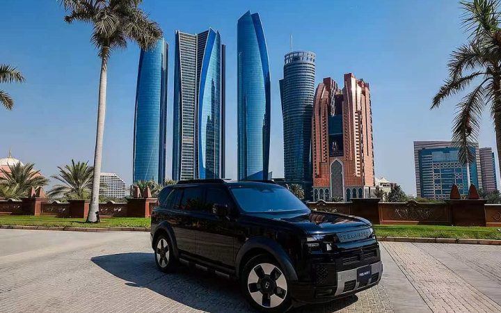 A black SUV parked in front of the modern Abu Dhabi skyline and palm trees under a blue sky