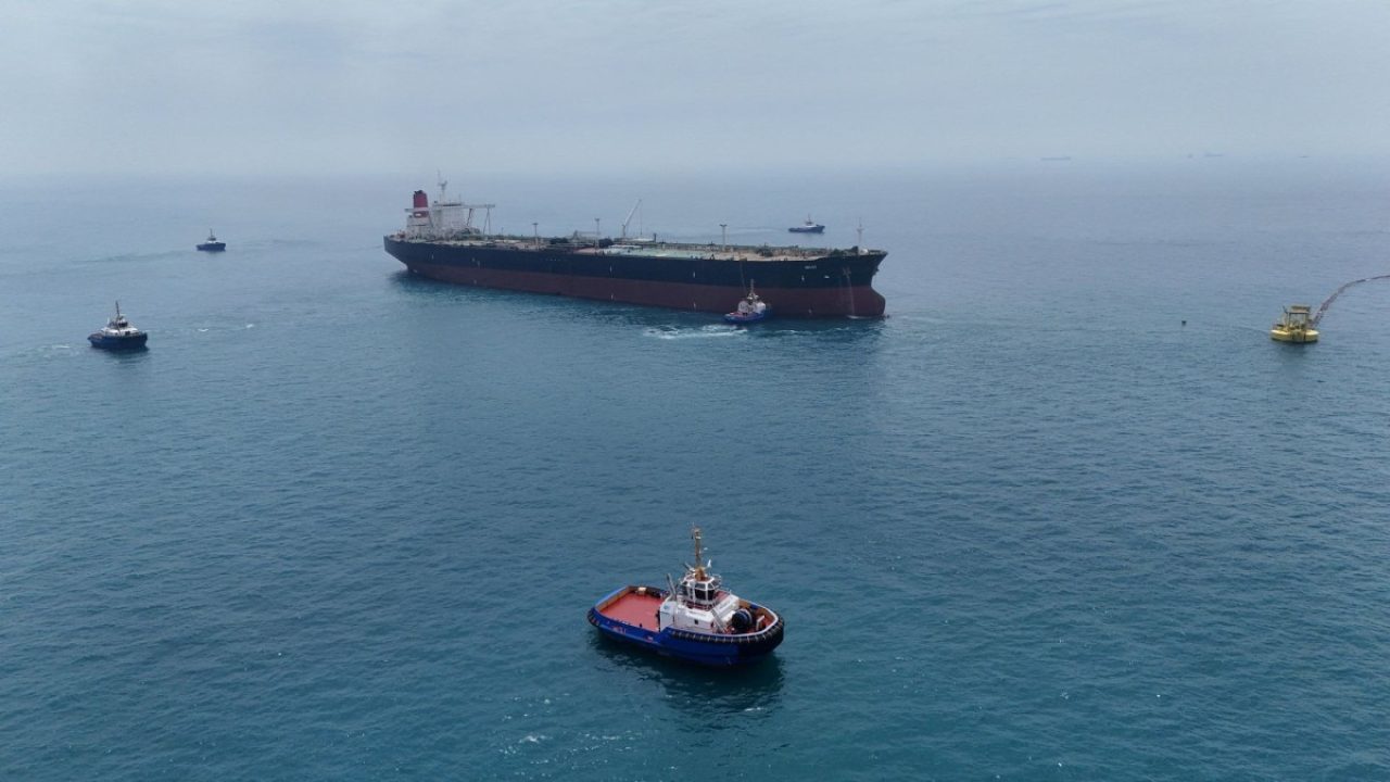 Large oil tanker and tugboats navigating open waters