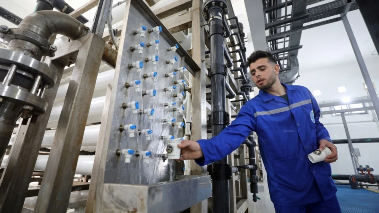 Technician in blue uniform testing water at an industrial desalination and filtration plant