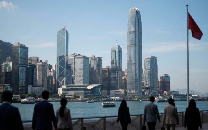Illustration: Editorial photograph showing modern financial skyscrapers in Hong Kong overlooking the harbour under a clear sky, with sleek glass archi