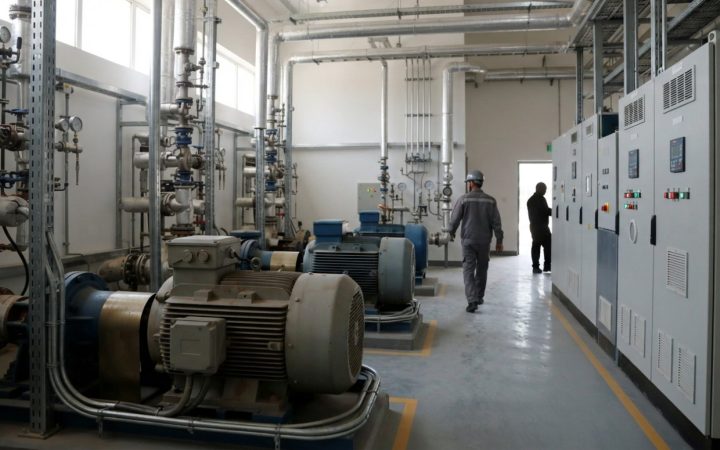 Illustration: A modern industrial equipment plant room showing large electric motors, high-pressure piping, and electronic variable speed drive contro