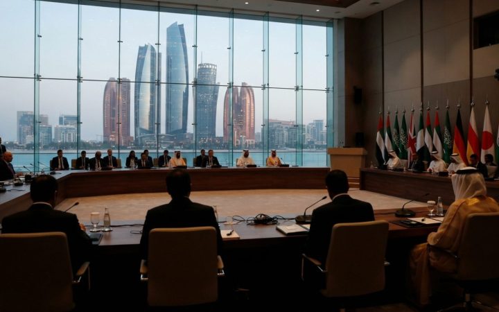 Illustration: A modern diplomatic conference room with international flags and conference tables, overlooking an urban commercial skyline in the Middl