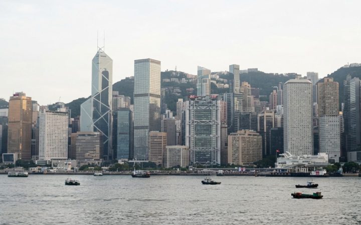 Illustration: Hong Kong's Central financial district skyline featuring modern glass high-rise bank towers bathed in soft daylight, shot from Victoria