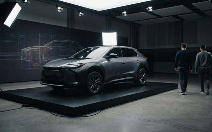 Illustration: A modern crossover vehicle on display on a sleek exhibition platform inside an industrial automotive design studio, dramatic studio ligh