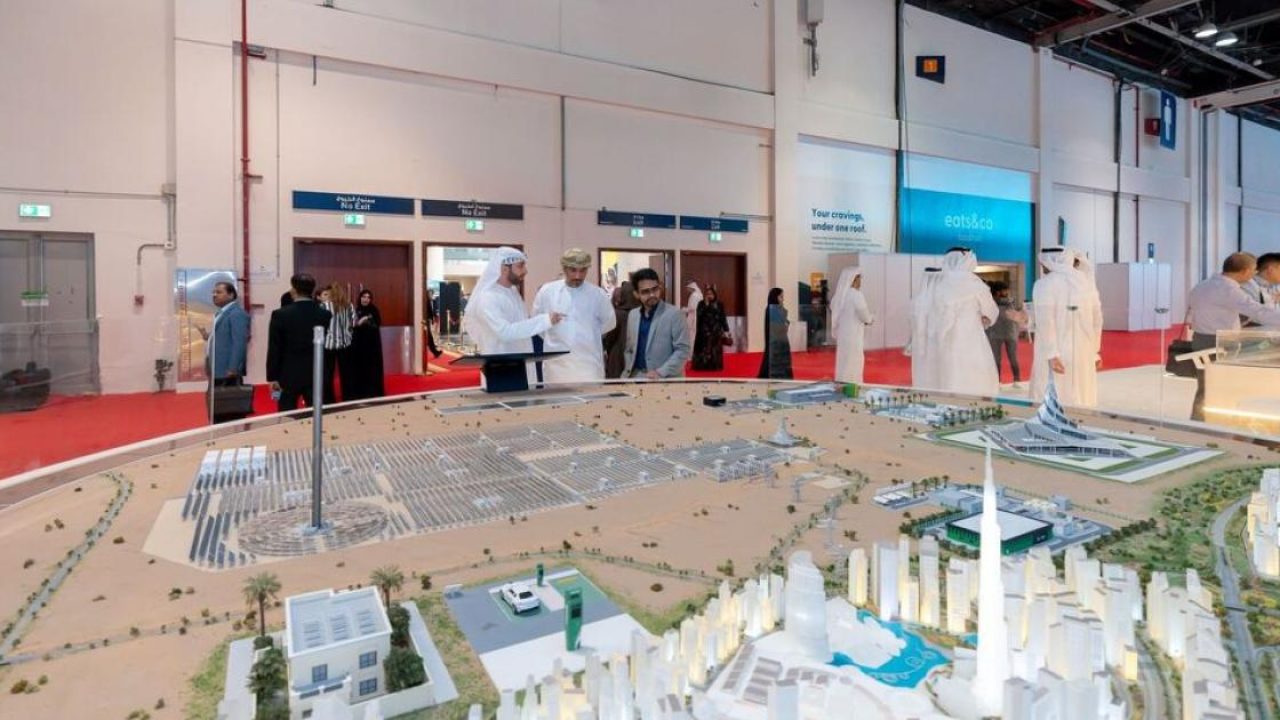 Attendees examining an architectural master plan model at an exhibition in the UAE