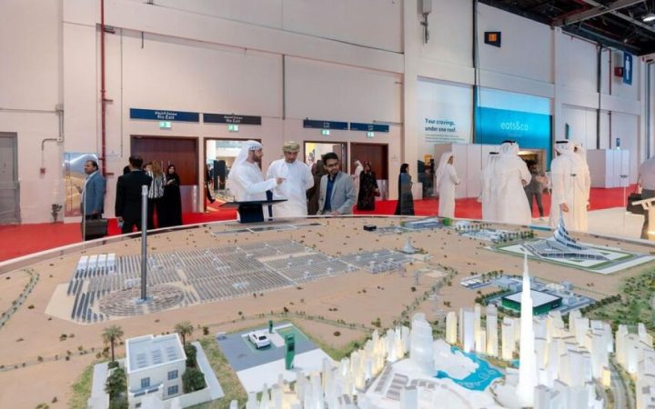 Attendees examining an architectural master plan model at an exhibition in the UAE