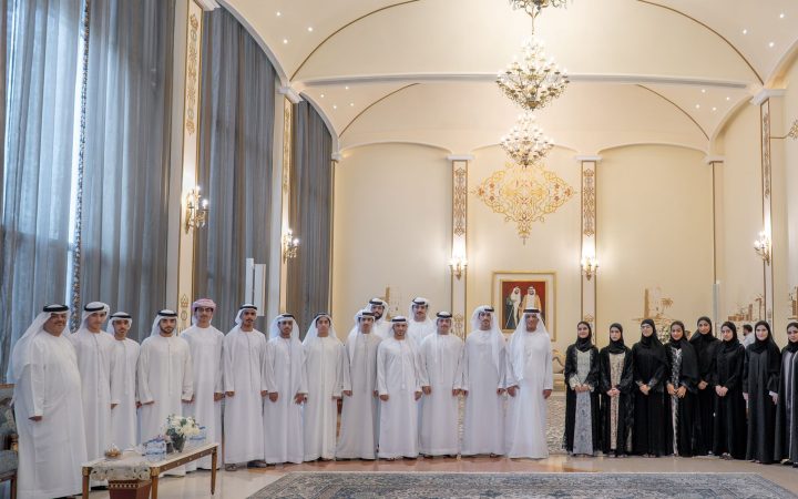 Group of Emirati men and women in traditional attire standing in an ornate reception hall
