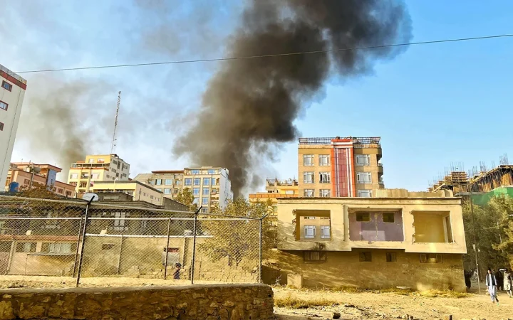 Dark smoke rising behind residential buildings in an urban area