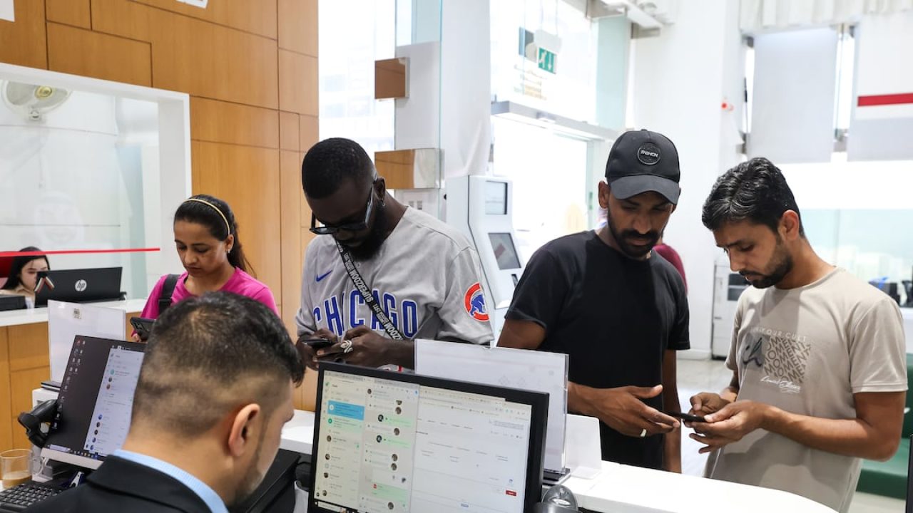 People standing at a customer service desk looking at their mobile phones
