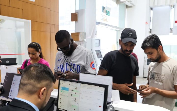 People standing at a customer service desk looking at their mobile phones