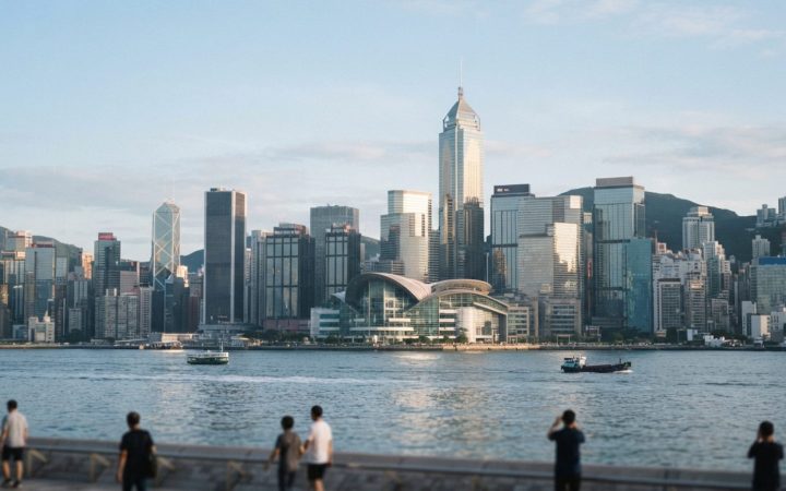 Illustration: Editorial photograph showing modern financial office buildings and glass skyscrapers of Hong Kong's Central district reflecting morning