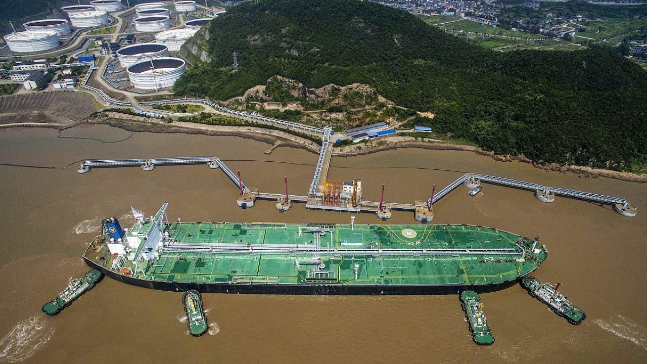 Aerial view of a large crude oil tanker docking at an offshore terminal jetty with tugboats